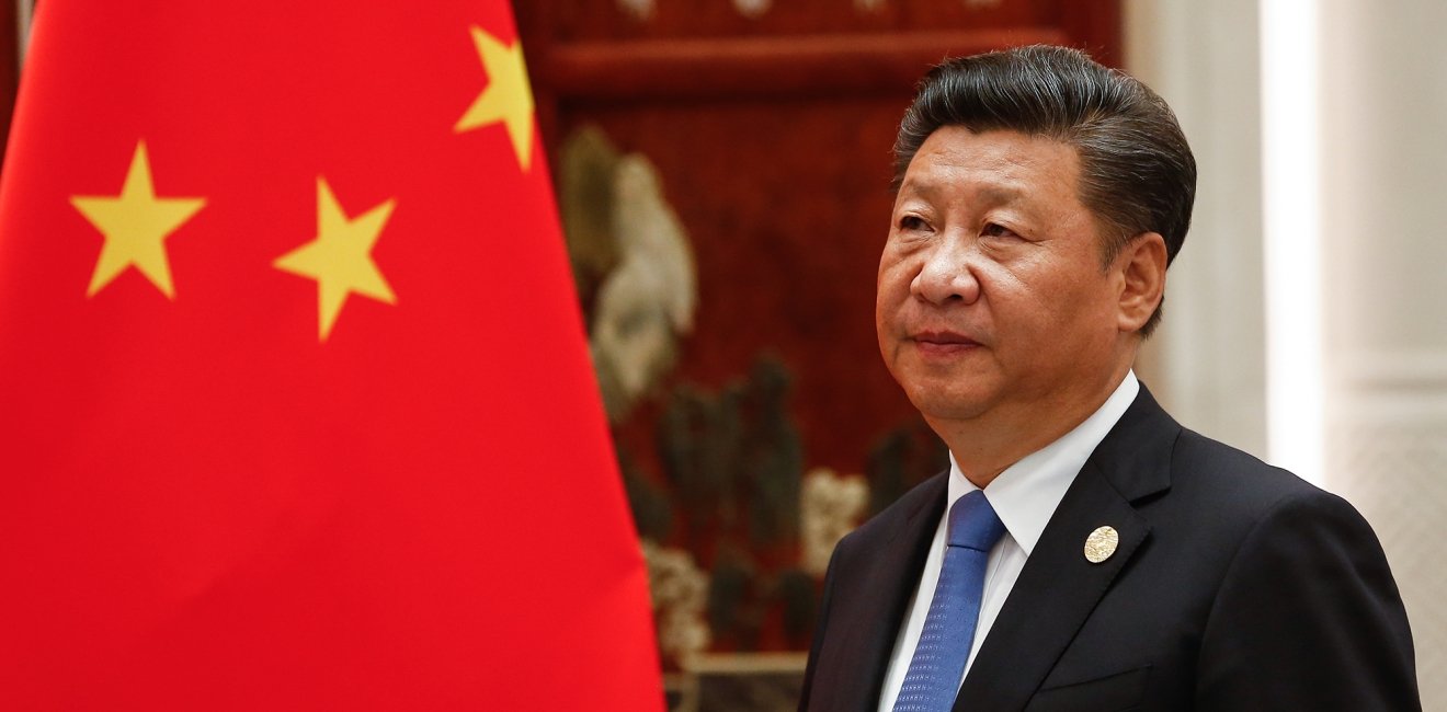 Xi Jinping standing next to the flag of China.