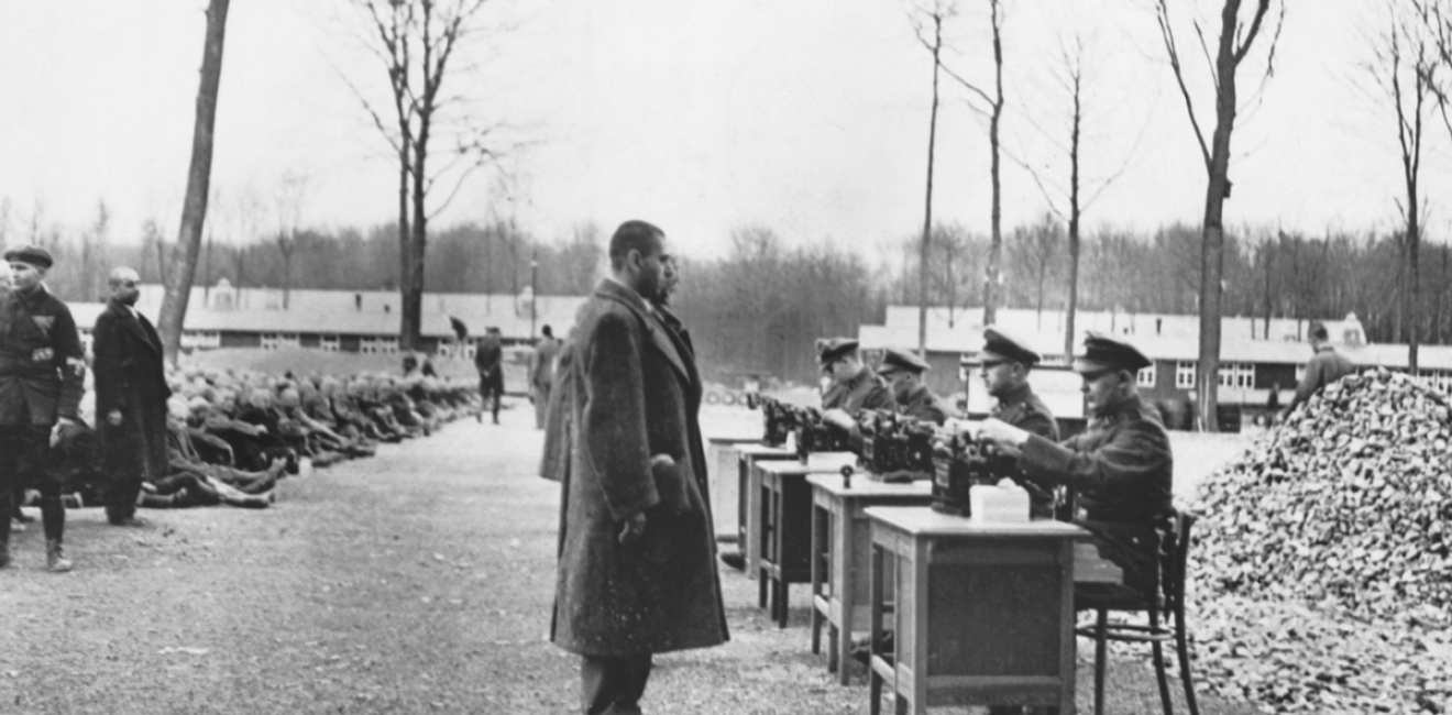 Gestapo officials recording data on incoming prisoners at a German concentration camp. Many others are seated on the ground