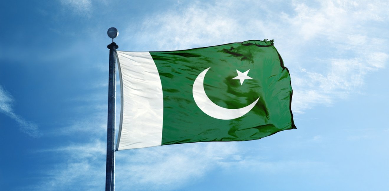 Pakistan flag against blue sky with some white clouds