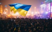 A Ukrainian flag is waved over a busy square. 