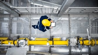 Man in a hardhat walking next to a pipeline