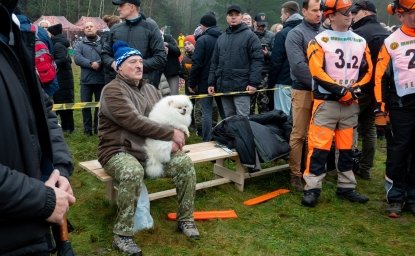 President Lukashenko sitting with a small white dog among a crowd of people 