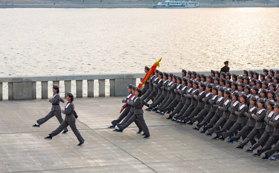 Squad of female teenagers in military uniforms rehearses for a parade