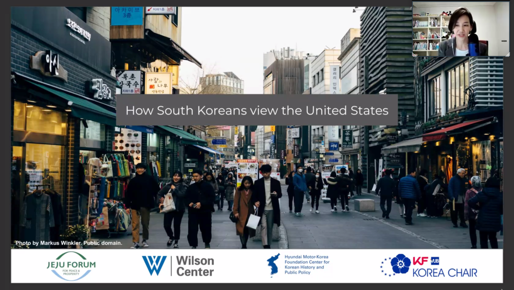 A screenshot of Dr. Kim Jiyoon speaking with a photo of people on the streets of Seoul in the background.