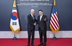 President Biden and President Yoon shaking hands in front of a banner announcing the official visit in 2022.