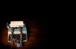 Typewriter locked with a chain and padlock on a black background