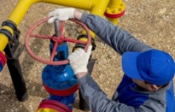 Image of a worker opening, closing the shut-off valves at the gas pumping station. Part of the photo is blurry.