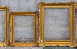 Three golden frames leaning against a wall