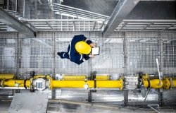 Man in a hardhat walking next to a pipeline